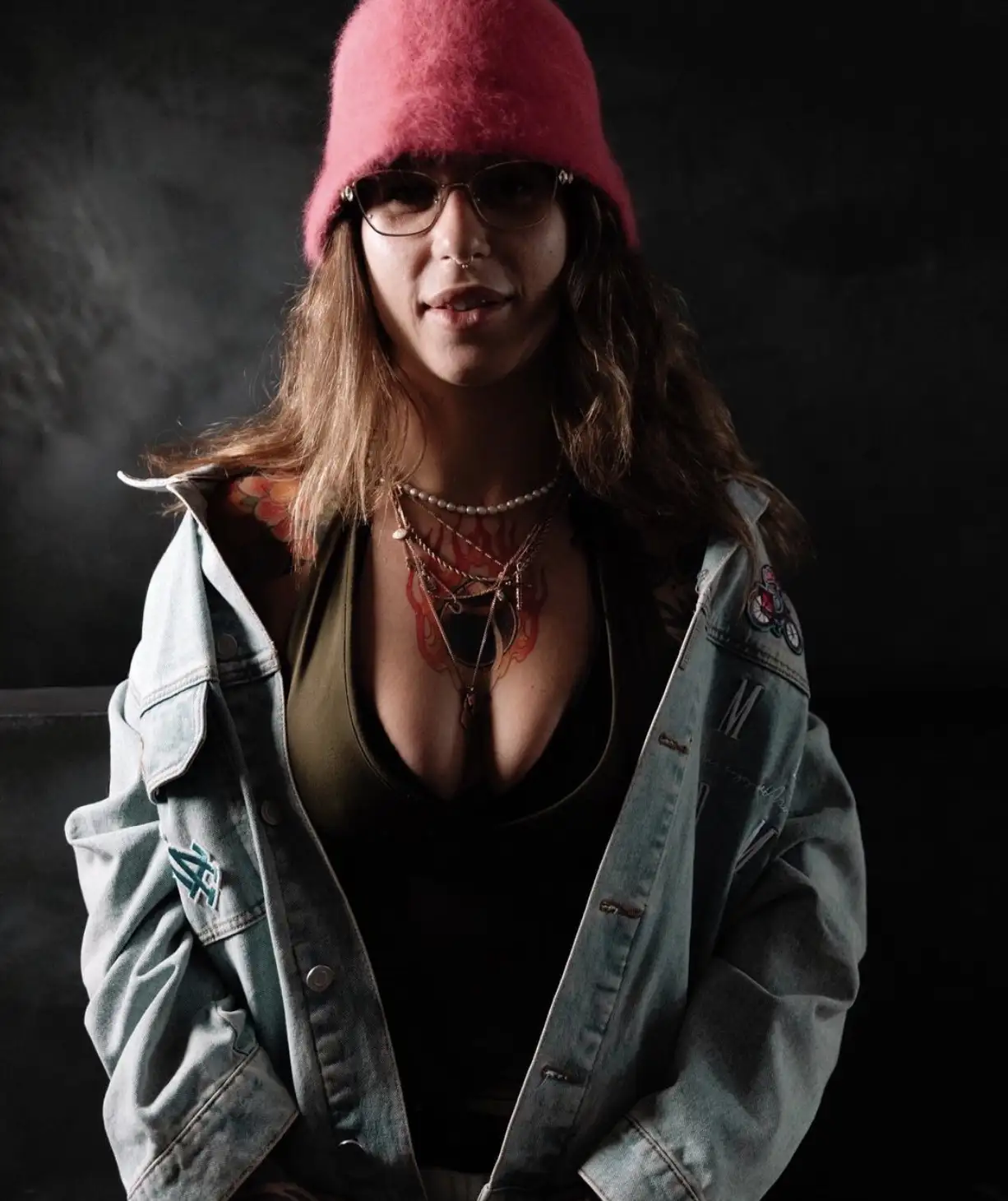 Portrait of tattoo artist Starzy wearing a pink hat and glasses.